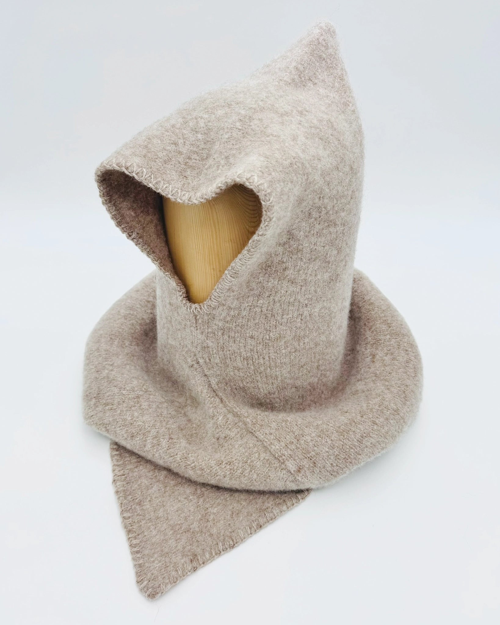 Produktfoto av lys brun Vikinghette fra Vikingstrikk, laget i myk ull med spiss hette og bred skulderkrage.